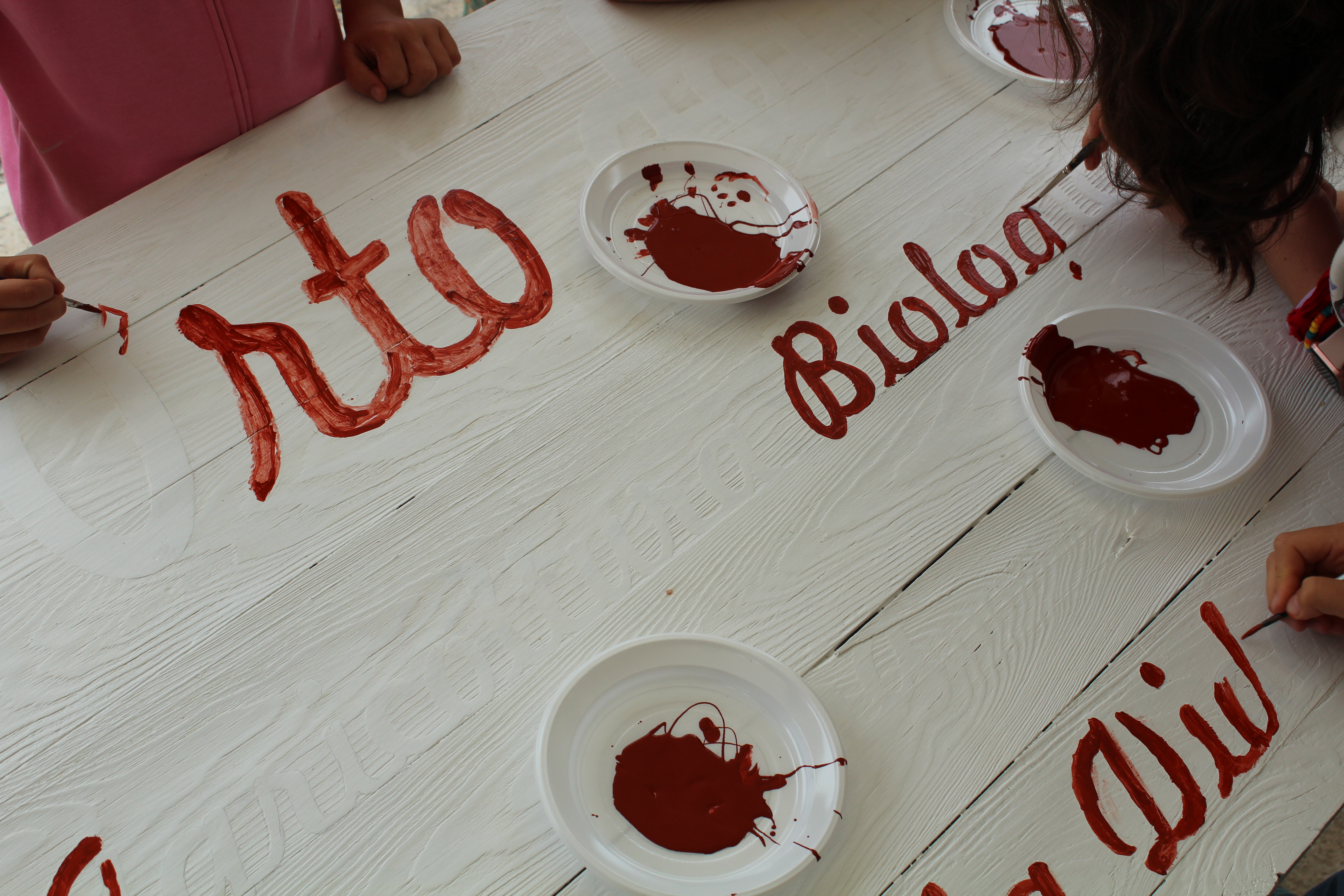 Bambini che dipingono l'insegna in legno del progetto educativo in natura